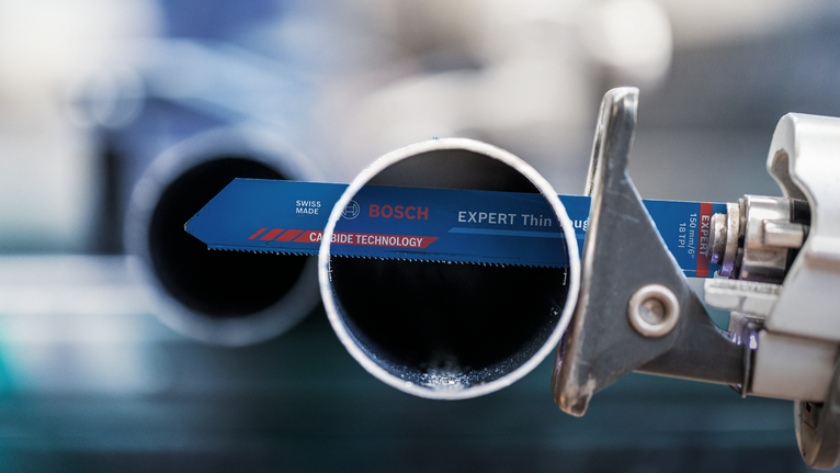 在工业环境中，往复锯片正在切割金属管道。