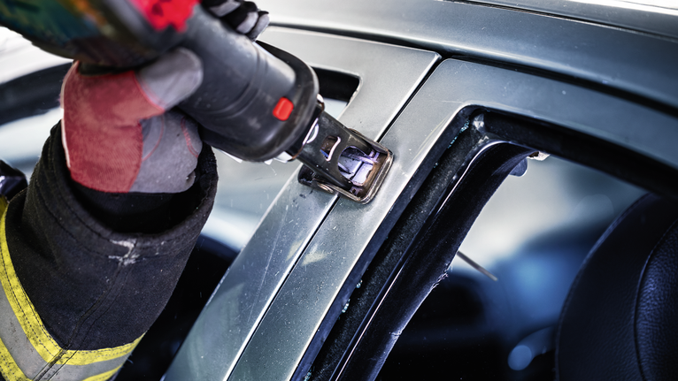 一名佩戴安全装备的人员使用电动工具切割汽车车架。