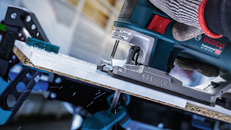 佩戴安全装备的人员操作曲线锯切割板材。