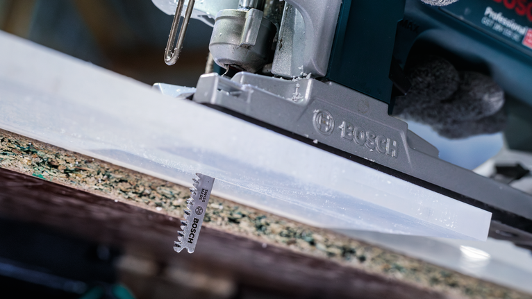 一名佩戴安全装备的人员操作曲线锯切割层压板。