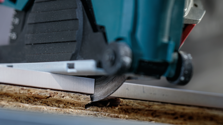 圆锯沿着金属导轨切割木板。