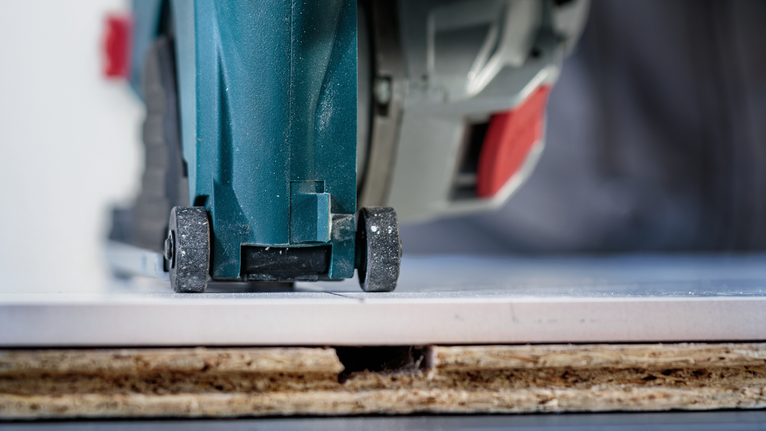 用圆锯切割安装在木质表面上的瓷砖。