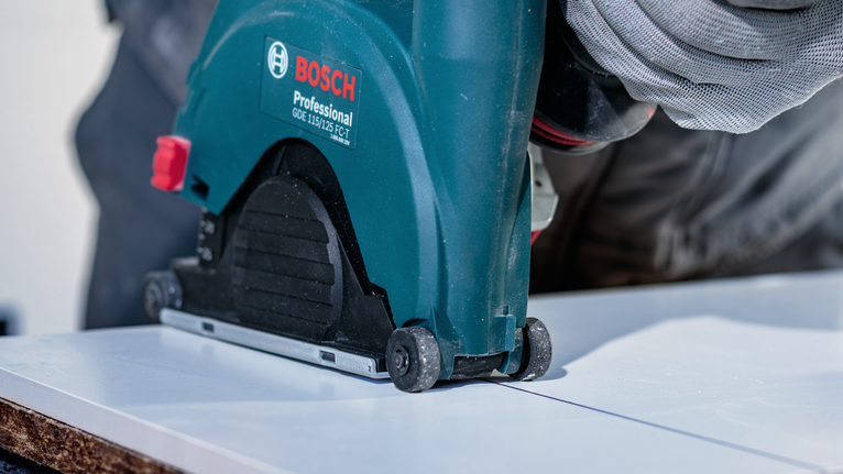 一名佩戴安全装备的人员正在引导电锯在木板上切割直线。