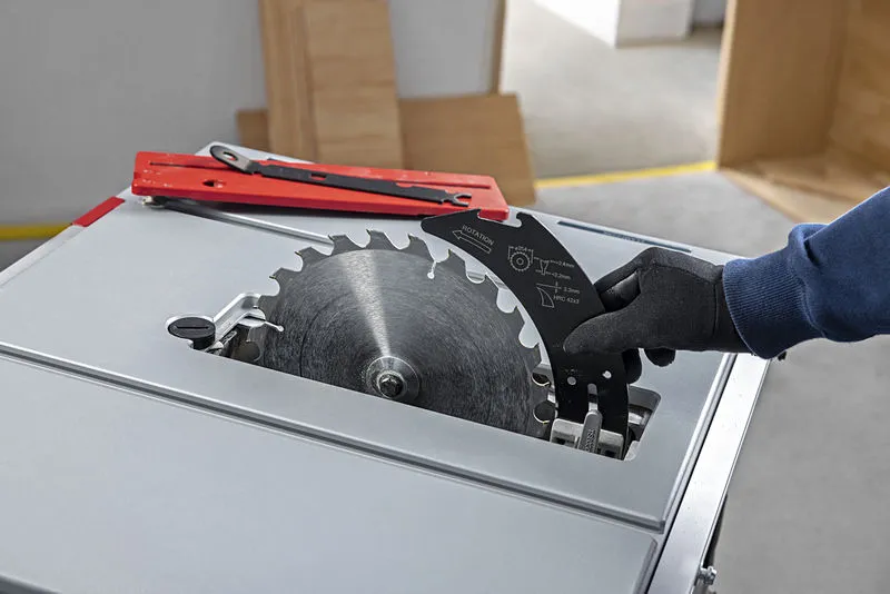 一名佩戴安全装备的人员正在更换台锯的锯片。