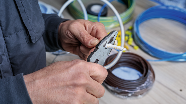 有人用钳子在盘绕的电缆附近剪断电线。