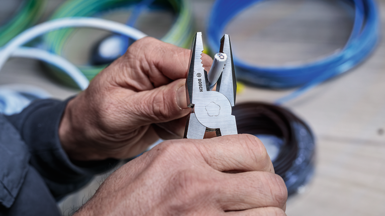 有人用钳子剥去电线上的绝缘层。