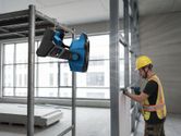 一名佩戴安全装备的人员在固定式便携式风扇附近操作电动工具。
