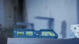 在建筑工地上，蓝色水平仪放在金属表面上。