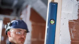 一名佩戴安全装备的人员正在建筑工地上调整垂直木梁的水平度。