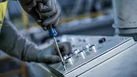 佩戴安全装备的人员使用螺丝刀将控制面板固定到控制设备上。