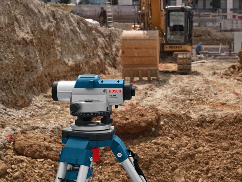 挖掘机附近建筑工地上三脚架上的激光调平工具。.